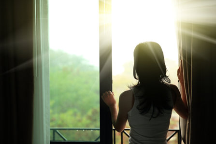 Young woman standing at a bright window. 